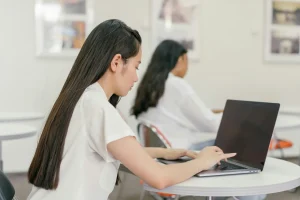 A student typing on her laptop in a class from behind