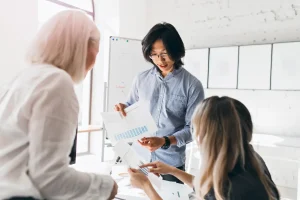Asian man showing a paper with graphics to women