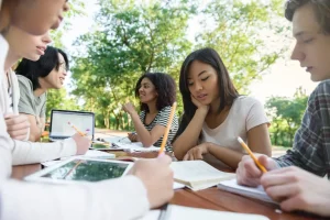 Multiethnic group of young students sitting and study together outdoor